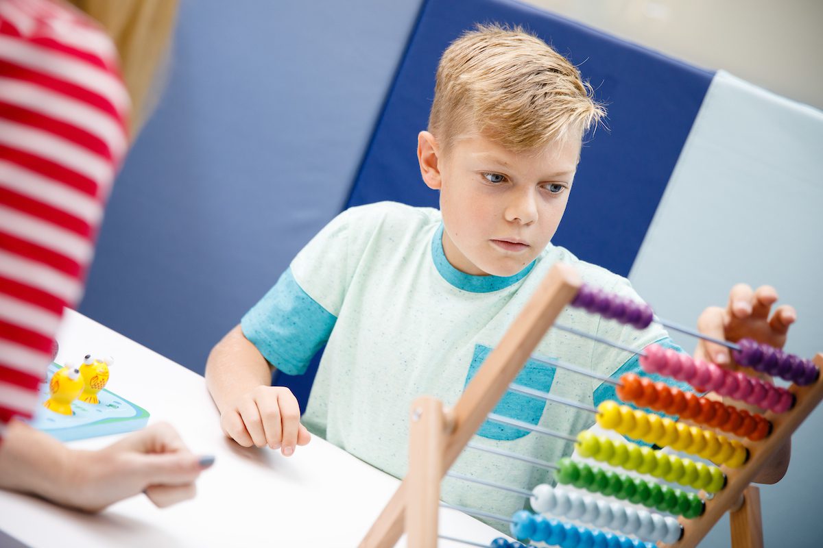 An autistic child enjoys playing while receiving developmental and behavioral guidance. 